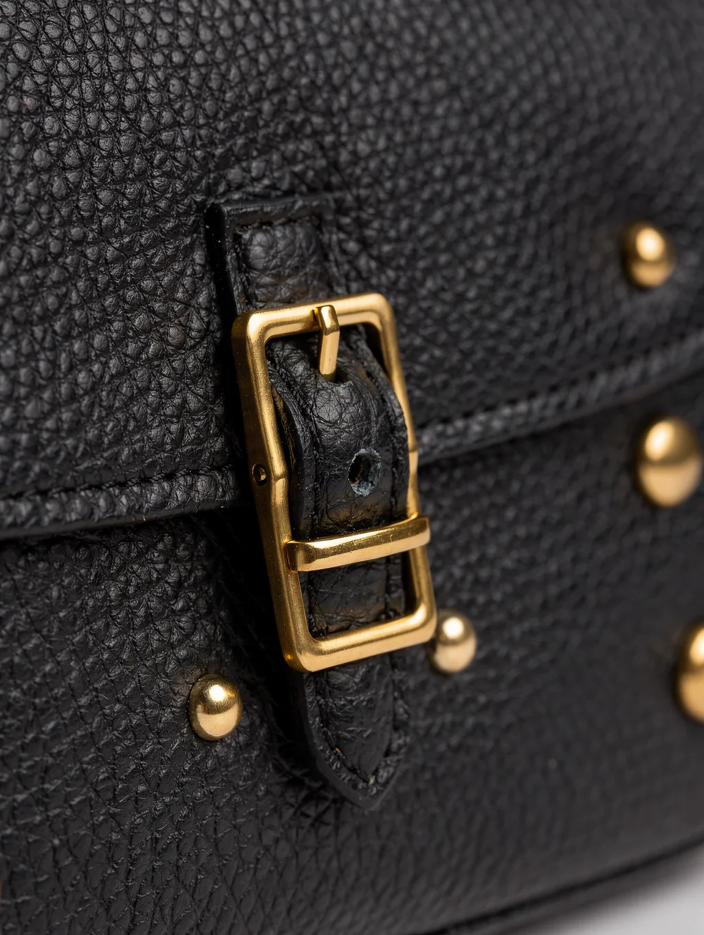 Macro texture of black pebbled luxury handbag leather with gold details